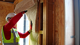Man installing insulation into wall | Shush! A Guide to Acoustic Insulation | Insulation Merchant